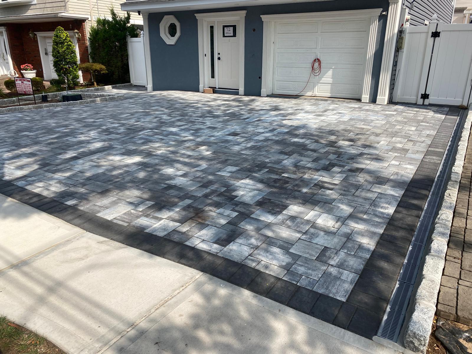 Completed backyard paver surface beside a pool and house