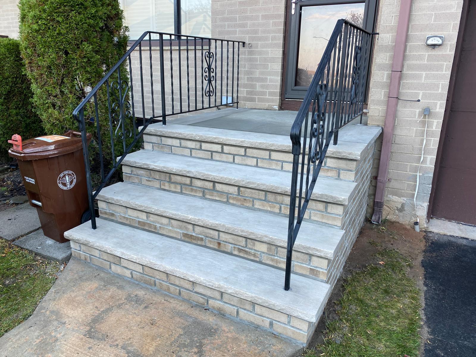 Front masonry steps with black railings